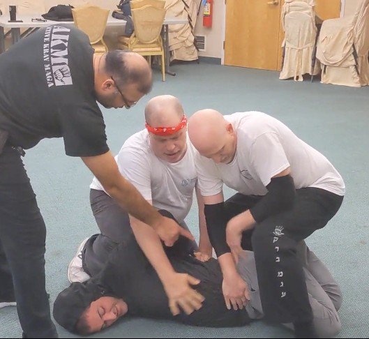 Practicing taking down pretend attacker Nadav Traeger were, from left, Avi Abraham, Mike Sigal, and Seth Speiser.